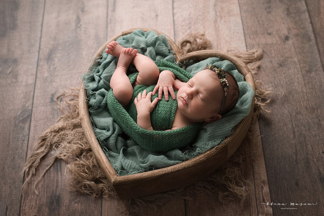 baby wrapped in green in heart basket